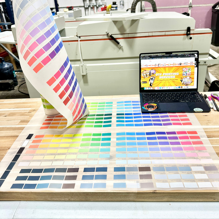 Color charts, transfer artwork and a laptop on a production worktable
